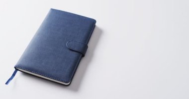 Kapalı mavi defteri beyaz arkaplanda yavaş çekimde kopyalayarak kapat. Boş zaman, okuma ve kitap okuma..