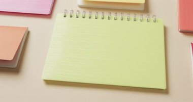 Bej arkaplan üzerine dizilmiş renkli defterleri yavaş çekimde kapat. Kırtasiye, öğrenim, okul ve eğitim kavramı.