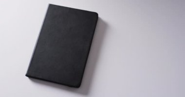 Kapalı siyah kitabı beyaz arka planda kopya alanı ile yavaş çekimde kapat. Edebiyat, okuma ve kitaplar.