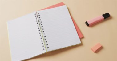 Bej arka planda okul kırtasiyesi olan açık defter görüntüsü, yavaş çekimde. Kırtasiye, öğrenim, okul ve eğitim kavramı.