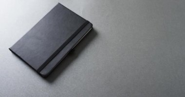 Gri arkaplan üzerine gri arkaplanı olan kapalı gri defteri yavaş çekimde kapat. Boş zaman, okuma ve kitap okuma..