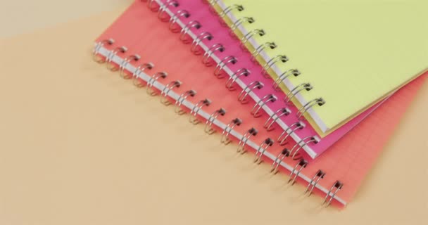 在米色背景上的彩色笔记本的头顶视图 慢镜头 文具用品 学校和教育概念 — 图库视频影像