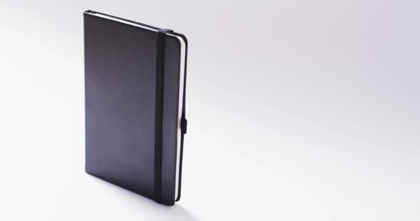 Закрытый Черный Ноутбук Стоящий Вертикально Копировальным Пространством Белом Фоне Замедленной — стоковое видео