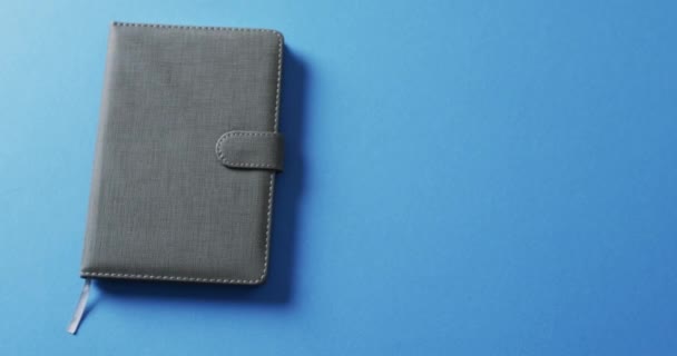 Close Van Gesloten Grijze Notebook Met Kopieerruimte Blauwe Achtergrond Slow — Stockvideo