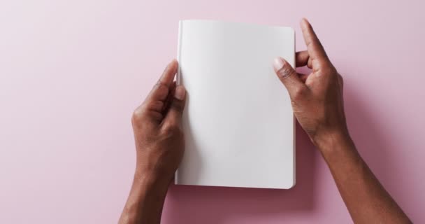 遅い動きのピンクの背景に黒いページのコピースペースが付いている本を保持している手の閉まり レジャー 創造性 — ストック動画