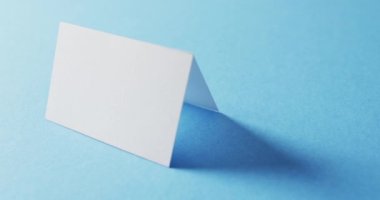 Mavi arkaplandaki iki beyaz kartviziti kapat, boşluğu kopyala, yavaş çekim. İş, iletişim detayları, modelleme, tasarım şablonu.