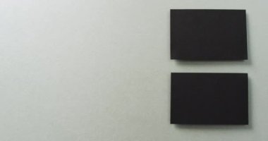 Gri arkaplanda düzenlenmiş iki siyah kartvizitin genel görünümü, kopyalama alanı, yavaş çekim. İş, iletişim detayları, modelleme, tasarım şablonu.