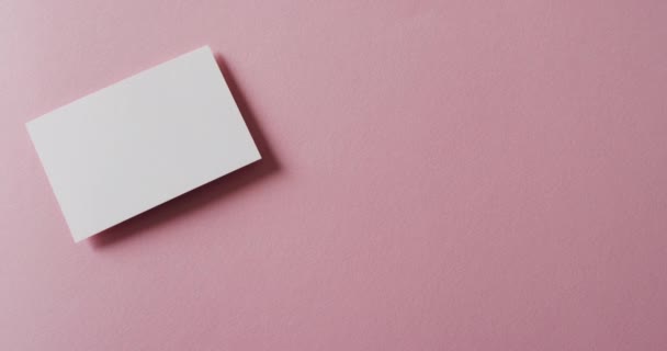ピンクの背景に空白の白い名刺 コピースペース スローモーション ビジネス 連絡先の詳細 モックアップ デザインのテンプレート — ストック動画