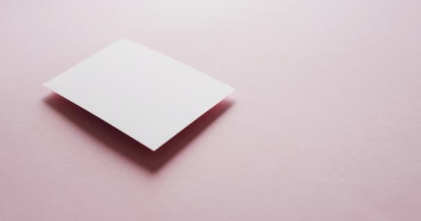 ピンクの背景 コピースペース スローモーションで空白のホワイトビジネスカードを閉じます ビジネス 連絡先の詳細 モックアップ デザインのテンプレート — ストック動画