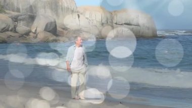 Sahilde yürüyen üzgün bir beyaz adamın üzerinde parlayan ışıkların animasyonu. Yalnızlık farkındalığı günü konsepti dijital olarak oluşturulmuş video.