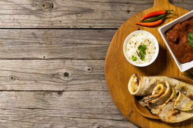 Pirinçli yassı ekmek ve kişniş ve kırmızı biberli et sosu servis masasında. Ahşap, tam yukarıda, Hint yemeği, değiştirilmemiş, yiyecek, taze ve yemek konsepti.