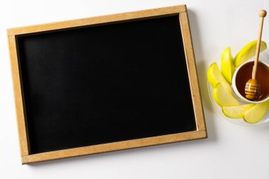 Masaüstü yazı tahtası ve bal manzarası, tabakta büyük anne demirci elması dilimleri olan bir kâse. eğitim, öğrenme, beyaz arkaplan, kopyalama alanı, tatlı yiyecek, meyve, yiyecek, sağlıklı, sonbahar mevsimi.