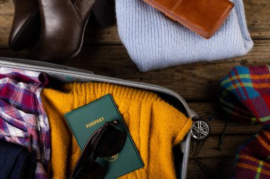 Kıyafet, güneş gözlüğü ve pasaport, çanta ve ayakkabılarla dolu bavul manzarası. Değiştirilmemiş, seyahat, bagaj, sıcak giysi, moda ve tatil konsepti.