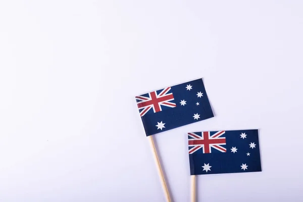Overhead view of small australian flags over white background, copy space. National flag, blue, patriotism and identity concept.