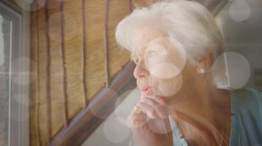 Üzgün, beyaz, yaşlı bir kadın üzerinde parlayan ışıkların animasyonu. Yalnızlık farkındalığı günü konsepti dijital olarak oluşturulmuş video.