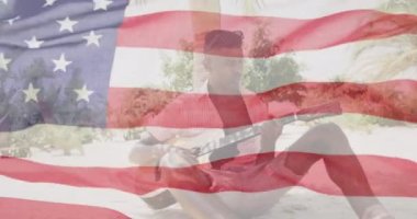 Sahilde gitar çalan Afro-Amerikan bir adam üzerinde Amerika bayrağı sallama animasyonu. Amerika, bağımsızlık günü, kutlama, gelenek, tatil ve vatanseverlik kavramı dijital olarak oluşturulmuş video.