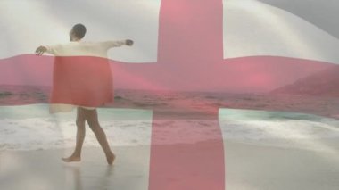 Sahilde suda oynayan mutlu Afrikalı Amerikalı kadın yerine İngiliz bayrağının animasyonu. Dijital bileşim, çoklu pozlama, tatil, boş zaman, özgürlük ve vatanseverlik kavramı.