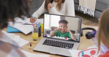 Farklı öğrenciler ekranda melez bir öğrenciyle video görüşmesi yapmak için dizüstü bilgisayar kullanıyor. İletişim, teknoloji, okul, öğrenme ve çevrimiçi eğitim, dijital kompozit video.