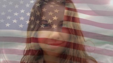 Amerikan bayrağının deniz kenarında gülümseyen melez kadının yakın çekimde dalgalanması. Dijital bileşim, çoklu pozlama, tatil, özgürlük, soyut ve vatanseverlik kavramı.