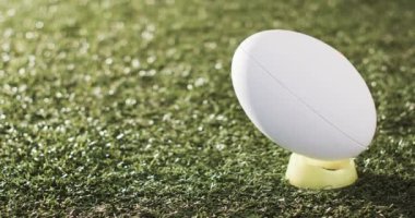 Beyaz rugby topu güneş ışığıyla aydınlatılmış çimlerin üzerinde fotokopi aletiyle, ağır çekimde. Rugby, spor, yarışma ve oyunlar dijital olarak oluşturuldu.