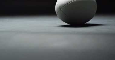 Siyah arka planda beyaz rugby topu, fotokopi alanı, yavaş çekim. Rugby, spor, yarışma ve oyunlar dijital olarak oluşturuldu.