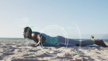 Sahilde kobra yoga pozu veren Afrikalı Amerikalı adamın dijital arayüzünün animasyonu. Küresel bağlantılar, refah, zindelik ve dijital olarak üretilen sağlıklı yaşam tarzı konsepti.