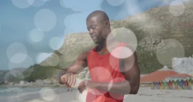 Sahilde akıllı adam kullanarak antrenman yapan Afro-Amerikan bir adamın üzerinde parlayan ışıkların animasyonu. Küresel bağlantılar, refah, zindelik ve dijital olarak üretilen sağlıklı yaşam tarzı konsepti.