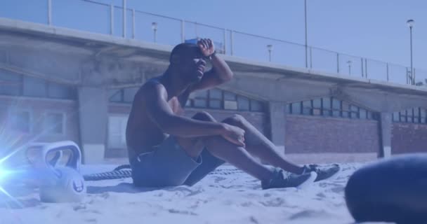 ビーチで休憩を取る太陽の下でアフリカ系アメリカ人の男の訓練の上に輝く光のアニメーション グローバル接続 フィットネス 健康的なライフスタイルコンセプトデジタルで生成されたビデオ — ストック動画