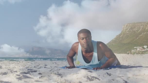 海岸でコブラヨガのポーズをしているアフリカ系アメリカ人男性の上に雲のアニメーション グローバル接続 フィットネス 健康的なライフスタイルコンセプトデジタルで生成されたビデオ — ストック動画
