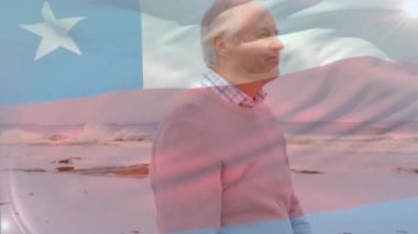 Sahilde dikilirken denize bakan yaşlı beyaz adamın üzerinde sallanan Şili bayrağının animasyonu. Dijital kompozit, çoklu pozlama, emeklilik, tatil, özgürlük ve vatanseverlik kavramı.