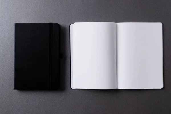黒いノートブックを閉じ 灰色の背景にコピースペースを持つ本を開きます — ストック写真
