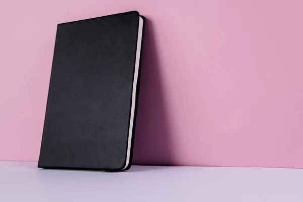 用粉红色背景的复制空间关闭黑色笔记本 闲暇时间和书籍 — 图库照片