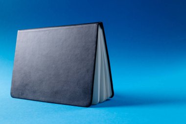 Mavi arkaplanda kopya alanı olan siyah defteri kapat. Edebiyat, okuma, yazma, boş zaman ve kitaplar..