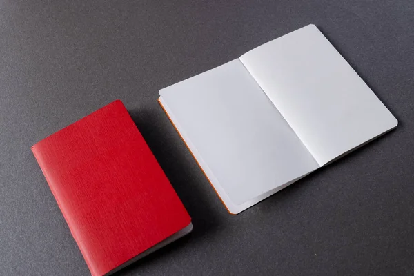 赤いノートブックを閉じて 灰色の背景にコピースペースを持つ本を開きます — ストック写真