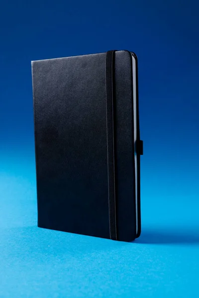 用蓝色背景的复制空间关闭黑色笔记本 闲暇时间和书籍 — 图库照片