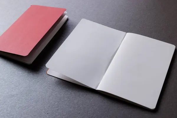赤いノートブックを閉じて 灰色の背景にコピースペースを持つ本を開きます — ストック写真
