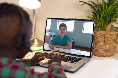 Çeşitli öğrenciler sıralarında oturuyor ve dizüstü bilgisayarlarından aranıyorlar. Okul, eğitim, teknoloji ve online öğrenim.