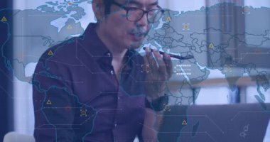 Akıllı telefondan konuşan ve ofiste dizüstü bilgisayar kullanan Asyalı adama karşı dünya haritasının animasyonu. Küresel ağ ve iş teknolojisi kavramı