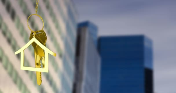 背の高い建物のぼやけた景色に対する黄金の家の鍵のアニメーション 不動産コンセプト — ストック動画