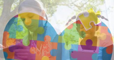 Çeşitli çocuklar üzerinde cep telefonu ve dijital tablet kullanarak kalp oluşturan yapboz parçalarının animasyonu. Dijital kompozit, çoklu pozlama, aşk, birliktelik, otizm farkındalık ve teknoloji konsepti.