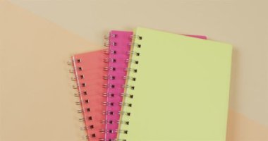 Turuncu arkaplanda ciltli ve kopya alanı olan üç defter. Okuma, öğrenme, okul ve eğitim kavramı.