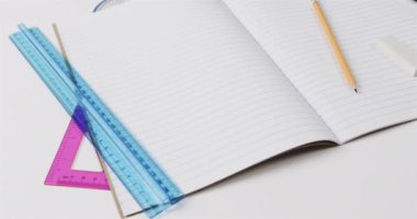 Okul kırtasiyesinin olduğu açık not defterini gri arka planda, yavaş çekimde kapat. Kırtasiye, öğrenim, okul ve eğitim kavramı.