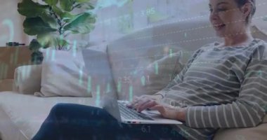 Evde dizüstü bilgisayarda çalışan beyaz bir kadın üzerinde birden fazla grafik ve alım satım tahtası animasyonu. Dijital bileşik, çoklu pozlama, rapor, iş dünyası, borsa ve teknoloji kavramı.