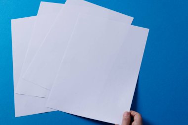 Beyaz bir kadının elinde kağıt parçalarının üzerinde mavi arka planda fotokopi alanı olan bir kağıt parçası. Edebiyat, okuma, boş zaman ve kitaplar..