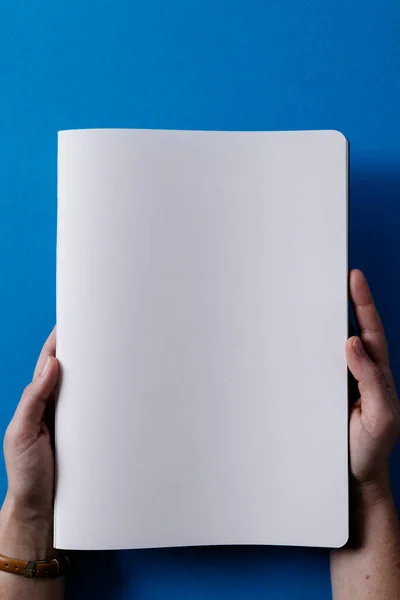 青い背景にコピースペースのある本を持つ白人女性の手 — ストック写真
