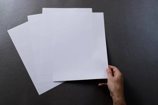 黒い背景にコピースペースを持つ紙の上に紙の作品を保持している白人女性の手 — ストック写真