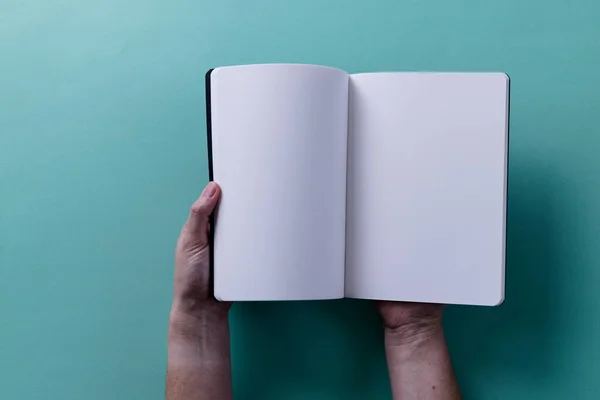 stock image Hands of caucasian woman holding book with copy space on green background. Literature, reading, leisure time and books.