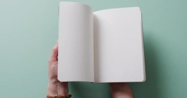 Yavaş çekimde yeşil arkaplan üzerine kopyalama alanı ile kitap boyunca el yapraklarını kapatın. Edebiyat, okuma, boş zaman ve kitaplar..