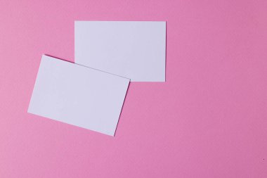 Pembe arka planda fotokopi alanı olan beyaz kartvizitler. İş, kartvizit, kırtasiye ve yazma alanı kavramı.