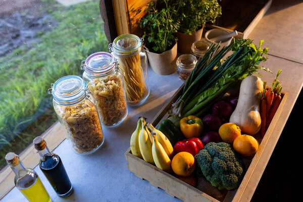 Crate of organic vegetables on countertop in sunny kitchen in log cabin. Food, nutrition, balanced diet and healthy living.